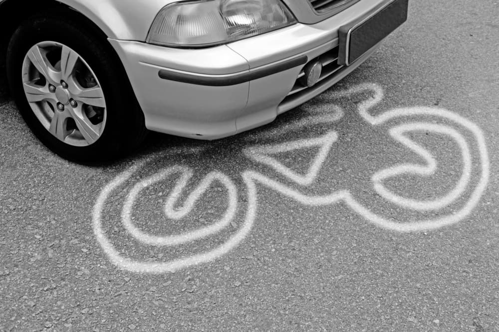 Bicycle victim chalk outline under a motor vehicle on a tarmac road. Concept: Bicycle commuting hazard.