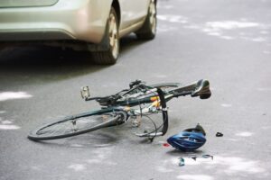 Bicycle and silver colored car accident on the road at forest at daytime.