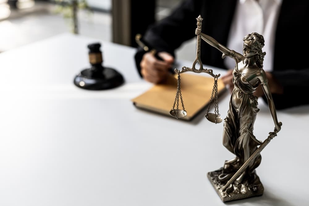 On the lawyer's desk, a statue of Themis, symbolizing justice, and a gavel. Concept of law and justice.