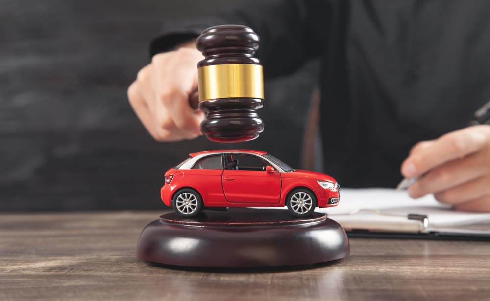 A judge striking a gavel next to a toy red car, symbolizing car accident legal cases.