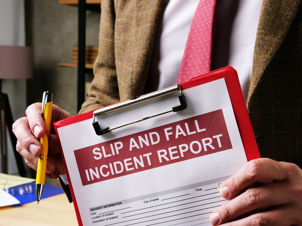 A person holding a clipboard with a "Slip and Fall Incident Report" form, ready to fill out.