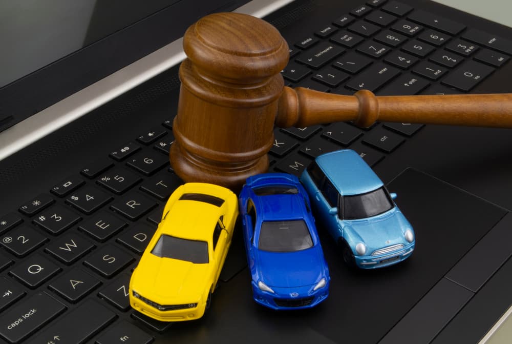 A gavel and three toy cars placed on a laptop keyboard, symbolizing car accident legal issues.