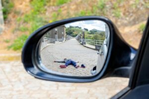 Fatal accident of a Pedestrian run over and lying dead on the road seen through the rearview mirror. Car insurance. Hit and run concept.